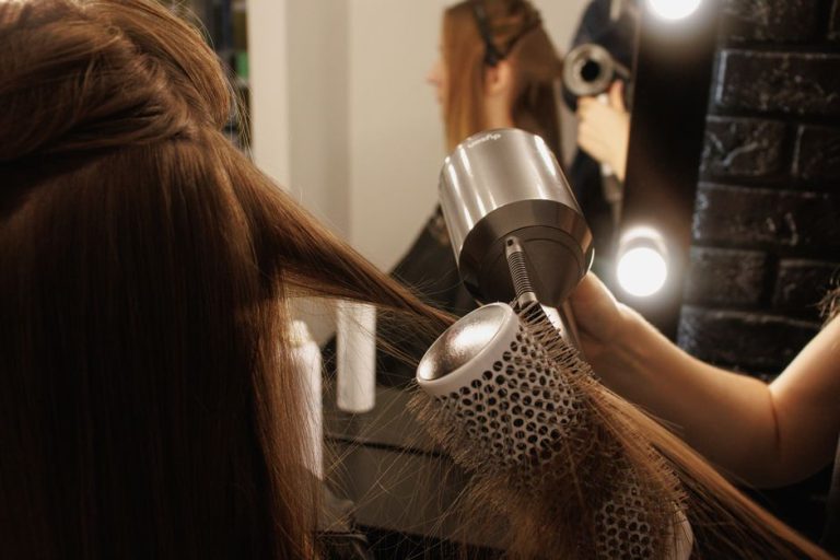Mujer secando su cabello con secador en el baño, cuidado capilar diario