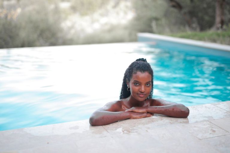 Mujer aplicando acondicionador en el cabello durante el verano junto a la piscina