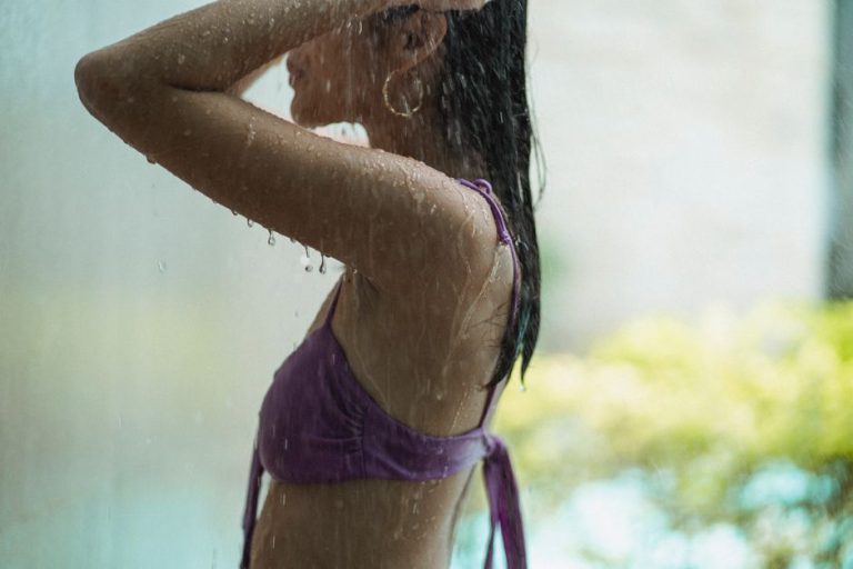 Mujer aclarando su cabello en una ducha de playa después de nadar