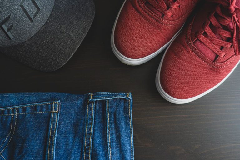 Diferentes cortes de vaqueros y accesorios de moda dispuestos sobre fondo neutro