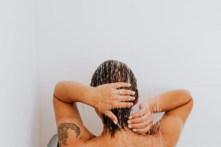 Mujer lavándose el cabello con champú en la ducha, rutina de cuidado capilar saludable