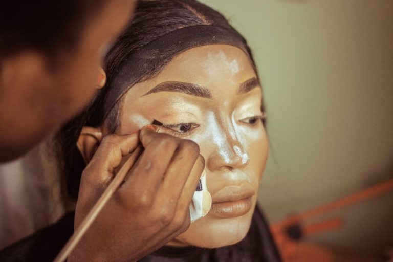 Primer plano de cepillo de cejas y productos de maquillaje sobre superficie neutra