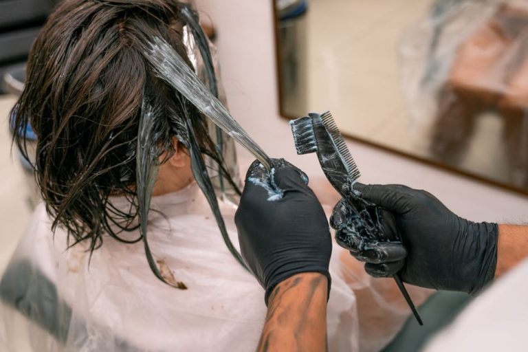 Colorista aplicando mechas en cabello castaño en salón de peluquería