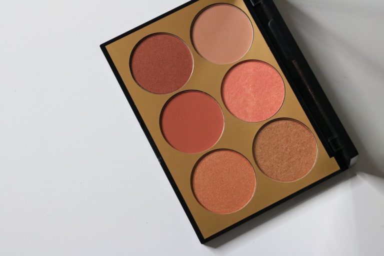 Paleta de sombras de ojos en tonos cálidos como melocotón, beige y bronce sobre fondo neutro