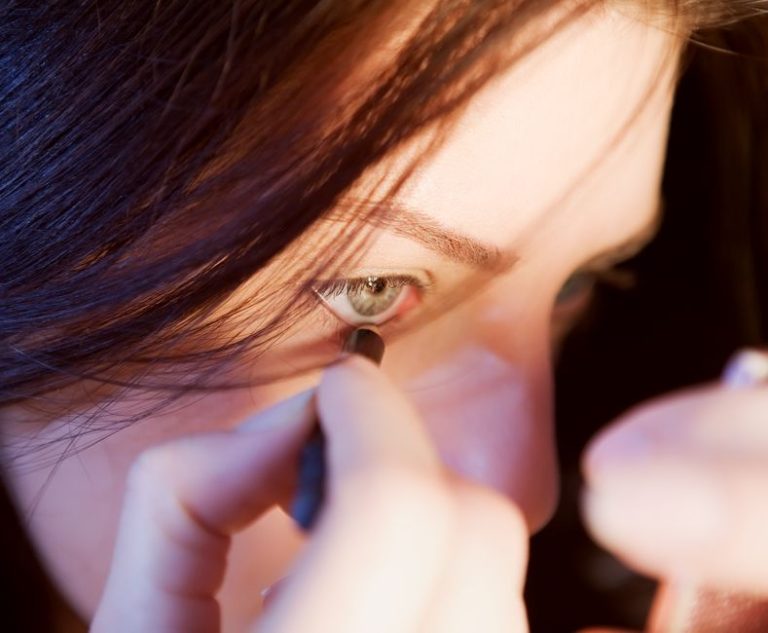 Primer plano de lápiz delineador y pincel de maquillaje sobre superficie neutra