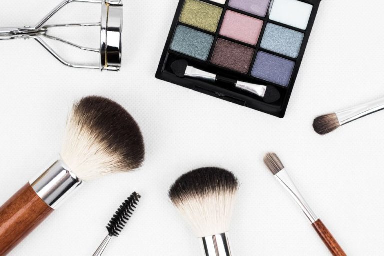Brocha de maquillaje aplicando polvos sobre compacto cosmético